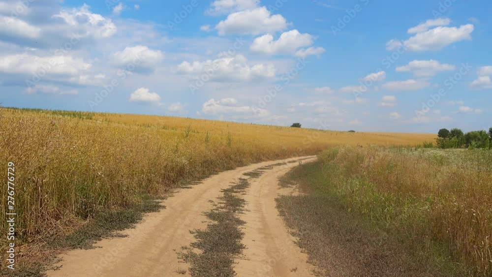 Driving on a country road view from the car window. View of the rural winding dirt road from the car. Driving on a country road view from the car window. View of the rural winding dirt road from the car.
