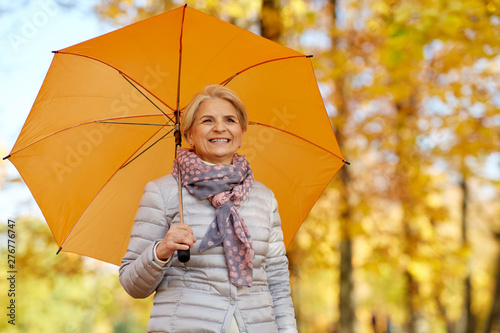 old age, weather and season concept - portrait of happy senior woman with umbrella at autumn park