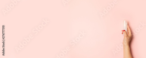 Womens hands hold intimate grease on a pink background