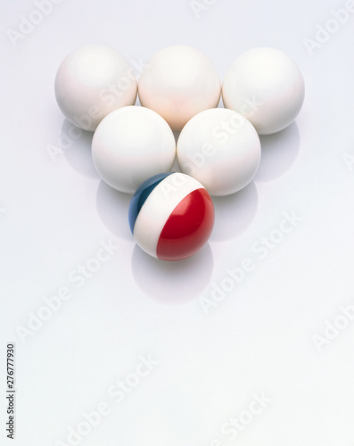 Five white balls with an odd ball in blue white and red colours 