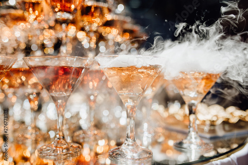 Many Glassware with Smoking Cocktail Beverage. Elegance Rich Buffet Decoration for Jubilee of Birthday or Wedding. Delicious Drink with Special Effect for Guests. Catering and Restaurant Service