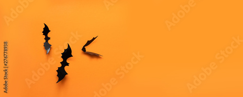 Creative top view halloween composition of black paper bats fly up on an orange background © Shi 