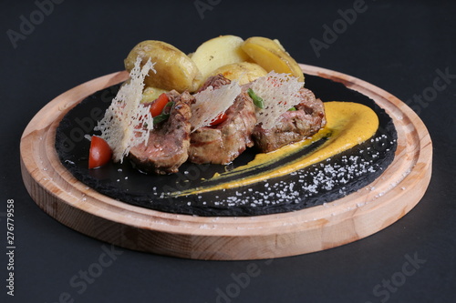 Beef and potato with mustard, tomato, grill, onion on black background.