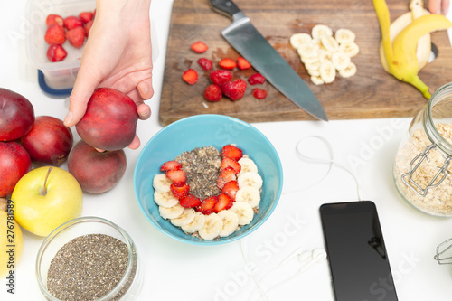 Woman preparing healthy fitness breakfast  oatmeal with bananas  strawberries and chia seeds