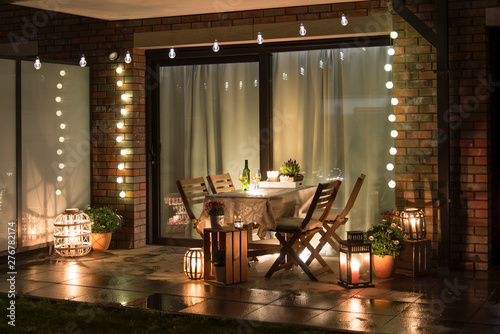 Fotografie, Obraz Summer evenig terrace with candles, wine and lights, after rain