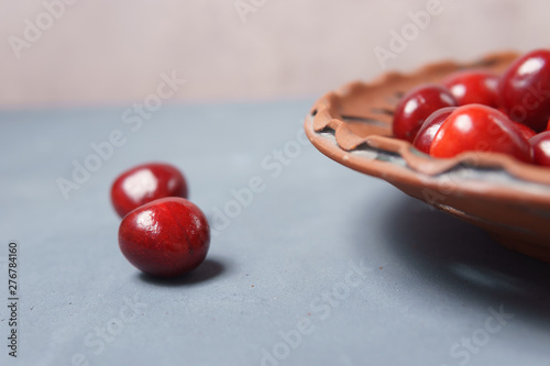 Red sweet cherry in a clay plate on a gray table