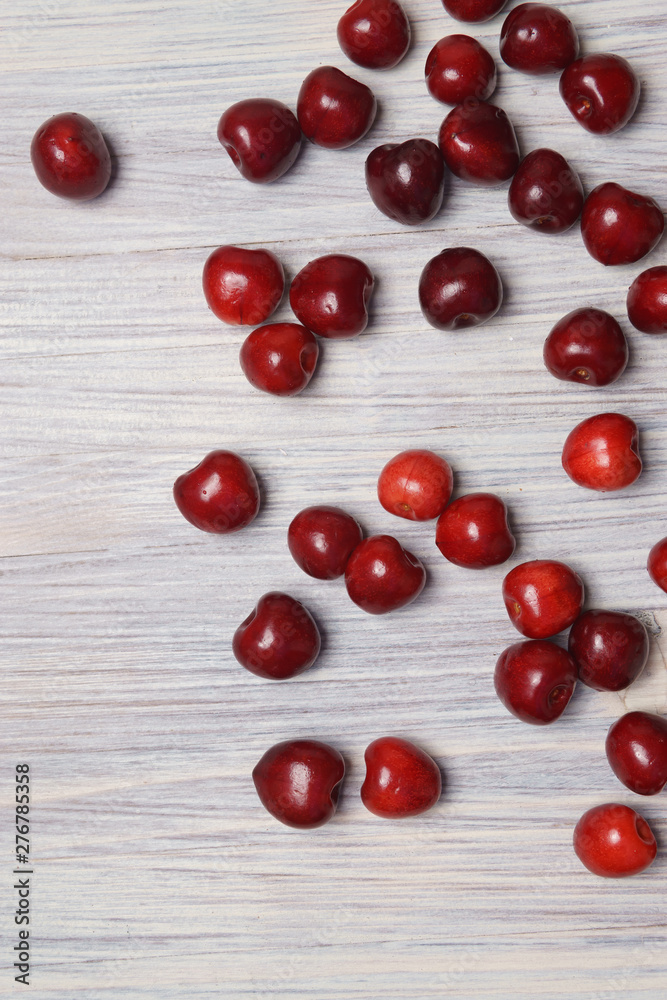 Red sweet cherry scattered on a white wooden table Red sweet cherry scattered on a white wooden table