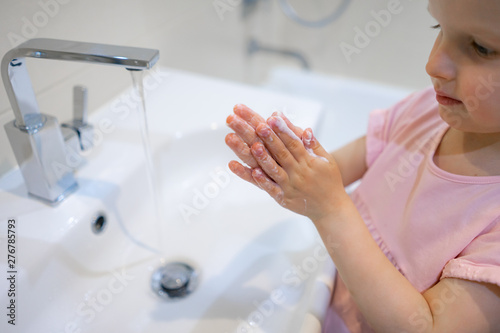Little girl washing her hands with soap 