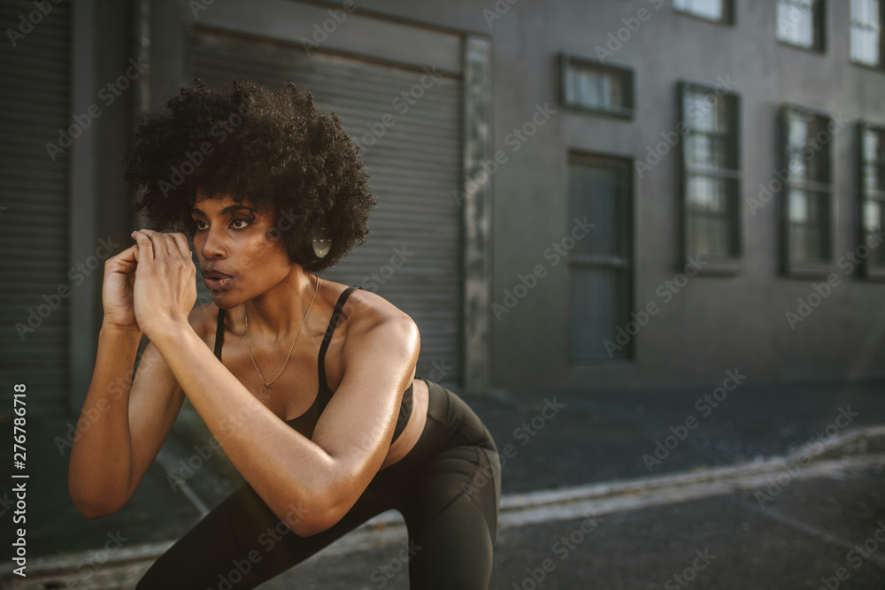 Young woman exercising squats in city - obrazy, fototapety, plakaty 
