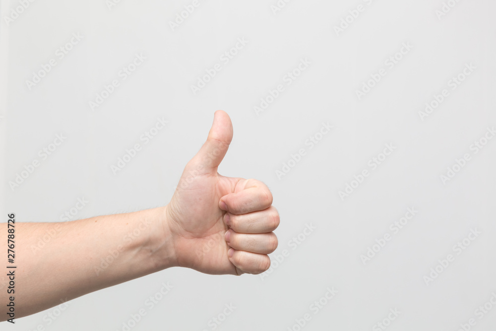 Closeup of male hand showing thumbs up sign against white background