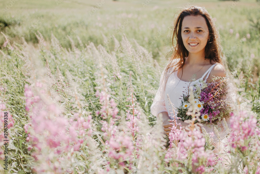 Portrait of a smiling woman close-up in a field with a flowering of willow, a woman holding a bouquet of wild flowers. Portrait of a smiling woman close-up in a field with a flowering of willow, a woman holding a bouquet of wild flowers.