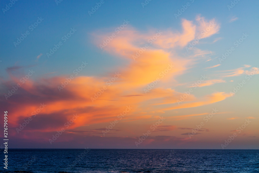 SEA LANDSCAPE WITH HORIZON OF HEAVEN AND CLOUDS ILLUMINATED BY THE SUNSET OF SUNSET.