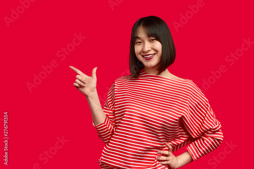 Positive Asian lady pointing aside photo