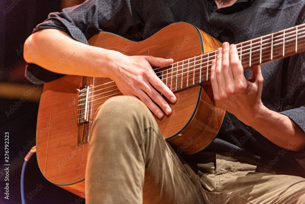 Obraz premium hands of musician playing Brazilian 7-string guitar on a stage