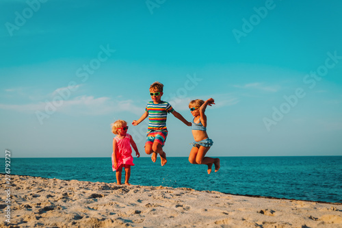 happy kids jump on beach, boy and girls having fun at sea
