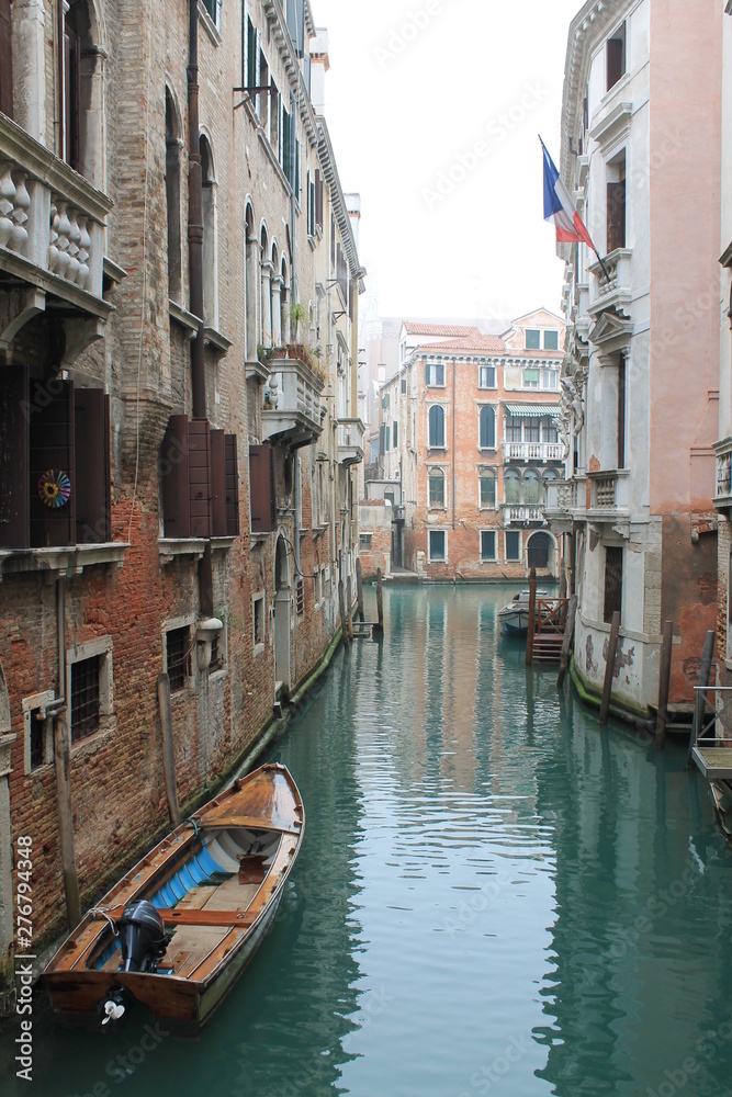 Canal in an overcast Venice with a parked boat