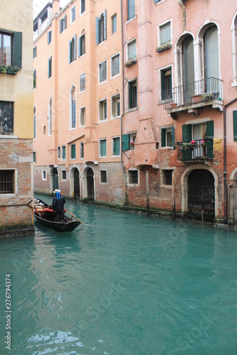 Gondolier on their Gondola cruising through a canal in Venice