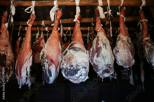 Smoked legs of ham in smokehouse. Whole ham hanging from the ceiling in farm. healing and drying of hams from Iberian pigs