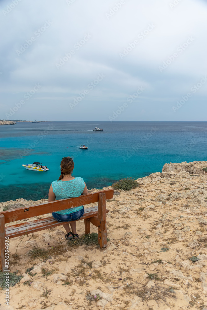 CYPRUS - MAY 11/2018: Tourist sits on a wooden bench near the blue lagoon.