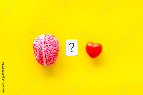 Emotions and mindfulness concept with brain and heart on yellow background top view