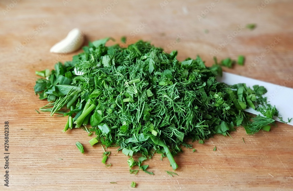 Chopped parsley and dill on a cutting board with a slice of garlic Chopped parsley and dill on a cutting board with a slice of garlic