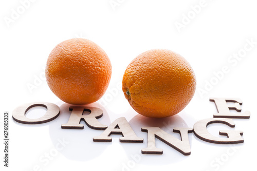 Two oranges and the word Orange. Isolated composition on white background with shadow.