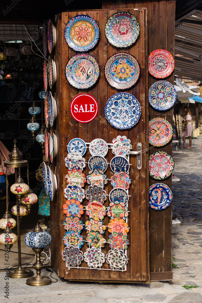Nesebar, Bulgaria-08.15.2018: Traditional bulgarian ceramic plates and dishes on wall in the street market. Colorful clay souvenirs hand painted. Ware in the national style shop in old town Nessebar