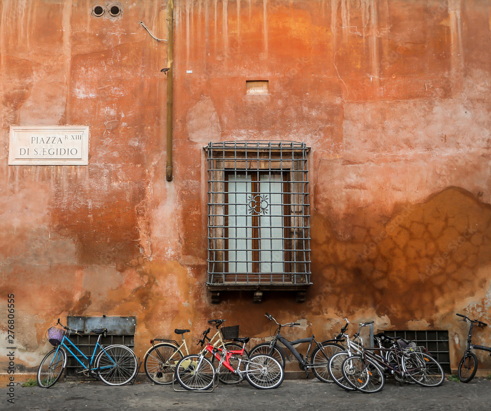 Bikes lean up against a colorful orange wall in Rome. 