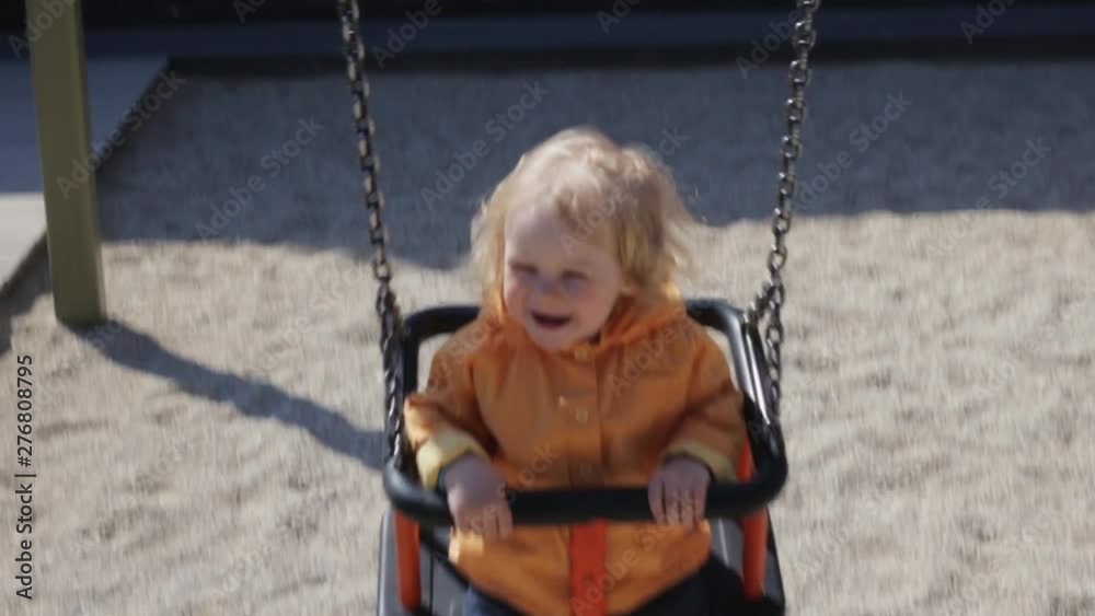 Cute little girl riding on a swing in the playground. Cheerful child resting in the park in the summer. Cute little girl riding on a swing in the playground. Cheerful child resting in the park in the summer.