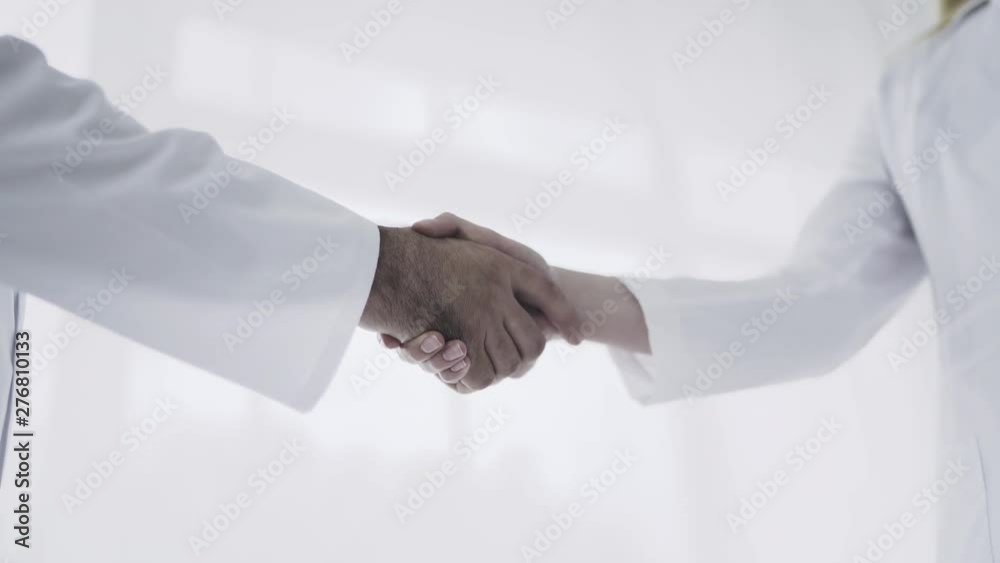 Two doctors is shaking hands to each other in medical space. Healthcare, medical concept Two doctors is shaking hands to each other in medical space. Healthcare, medical concept