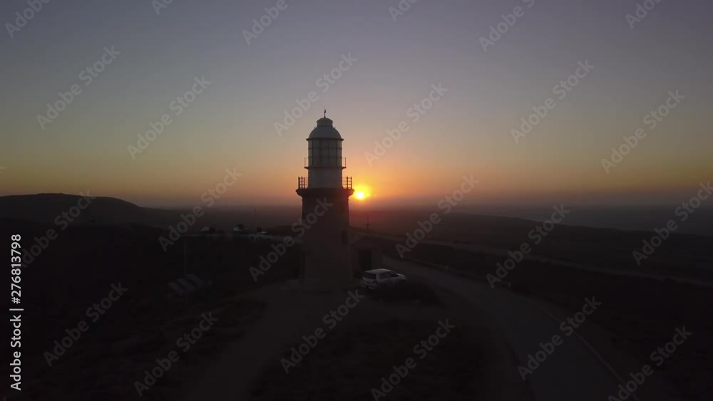 the red australian desert sun sets behind a lighthouse. Aerial view of the Australian coast with an impressive sunset