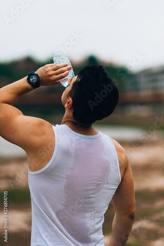 Fototapeta Naklejka Na Ścianę i Meble -  A man thirsty eagerly drinking water from plastic bottle