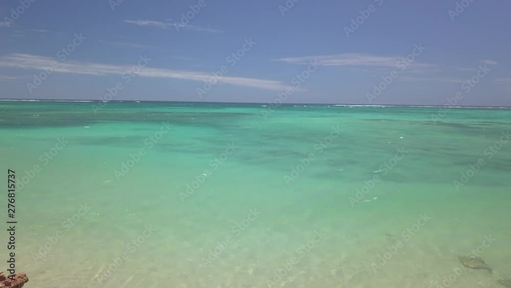 Drone flies over the endless beaches of the Australian Coral Bay. The blue sky with its small white clouds is reflected in the crystal clear waters of the Indian Ocean Drone flies over the endless beaches of the Australian Coral Bay. The blue sky with its small white clouds is reflected in the crystal clear waters of the Indian Ocean