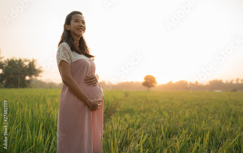 beautiful pregnant woman in rice field on sunset day photo