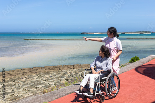 車いすで散歩するシニアと介護ヘルパー © imacoconut