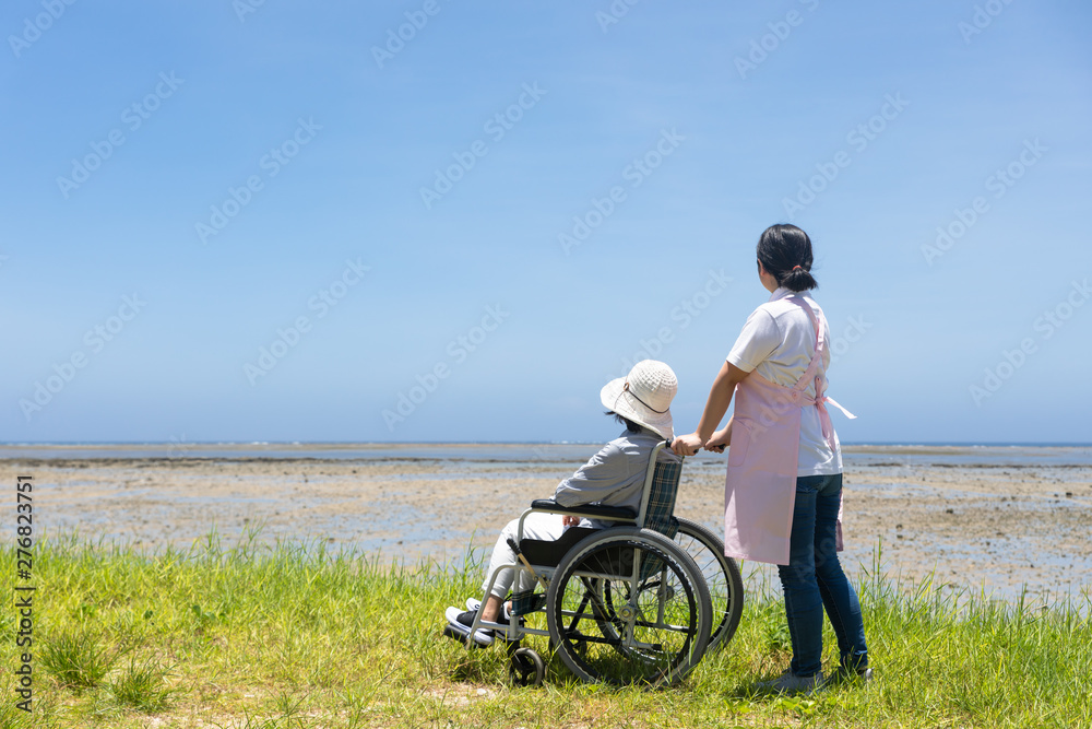 車いすで散歩するシニアと介護ヘルパー