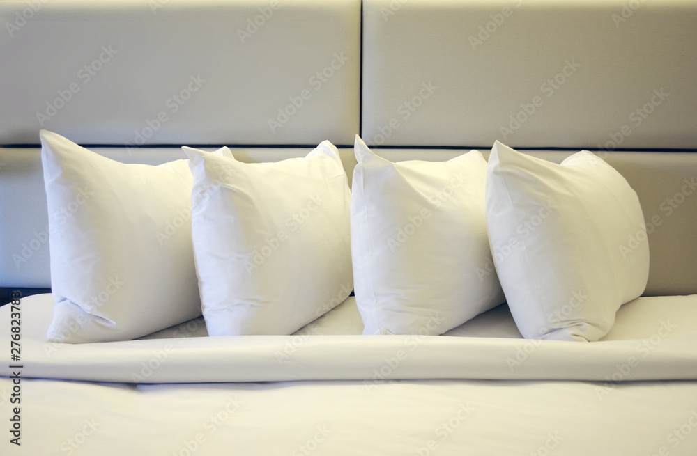 Obraz premium Close view of four pillows on a freshly made hotel bed 