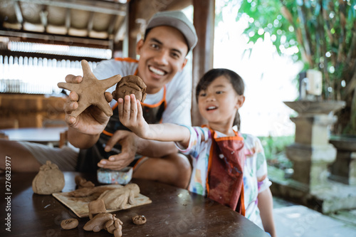 asian father and daughter making pottery together with clay
