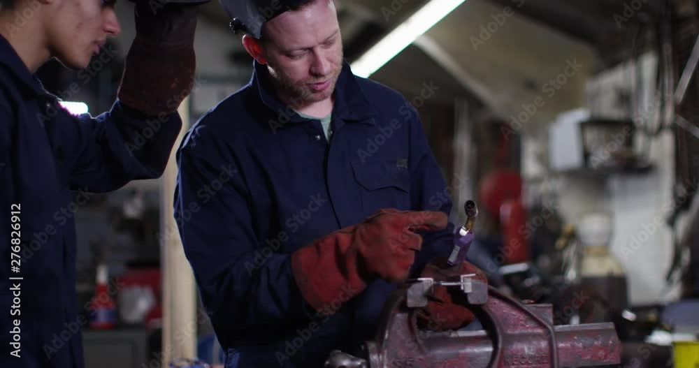 4K Experienced mechanic teaching young apprentice how to weld metal in workshop. Slow motion. 4K Experienced mechanic teaching young apprentice how to weld metal in workshop. Slow motion.