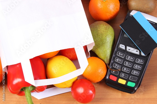 Fototapeta Naklejka Na Ścianę i Meble -  Payment terminal, contactless credit card, paper shopping bag with fruits and vegetables