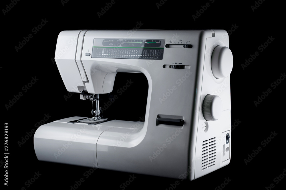 Electromechanical modern white plastic sewing machine on a black background, isolate
