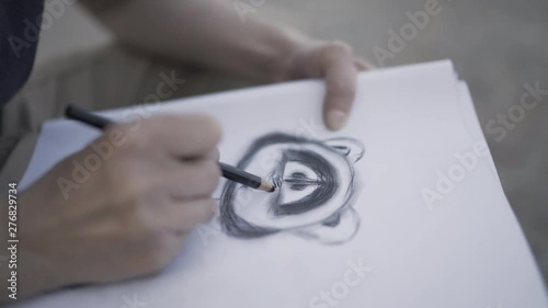 Woman is drawing with pencil sketch of raccoon. Artist is working on a project photo