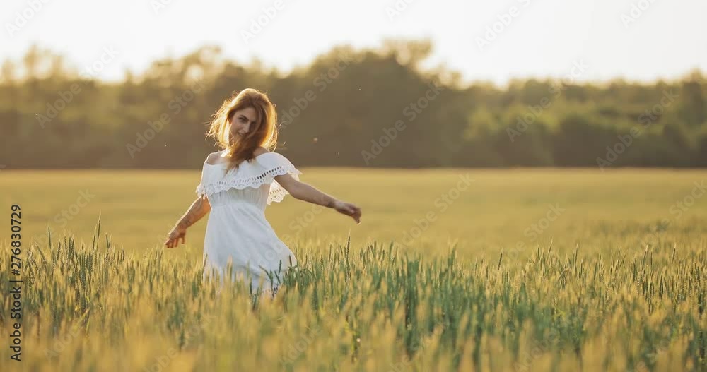 Happy girl whirls in a wheat field. Beautiful woman running through the green grass. Happy girl whirls in a wheat field. Beautiful woman running through the green grass.