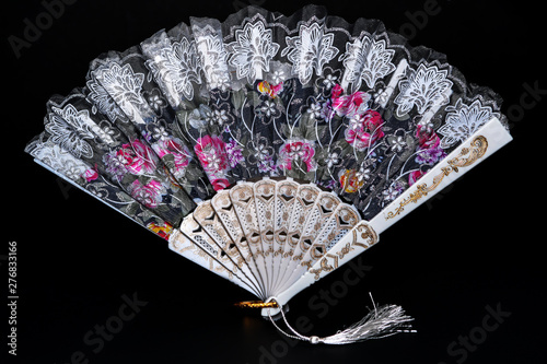 Flamenco hand fan with colorful pattern isolated on black background