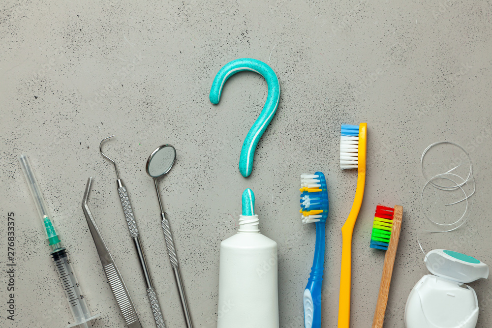 Toothpaste in the form of a question mark and many different and colored toothbrushes and dental floss, dental tool. Concept of how to choose the right toothbrush or how to brush your teeth - obrazy, fototapety, plakaty 