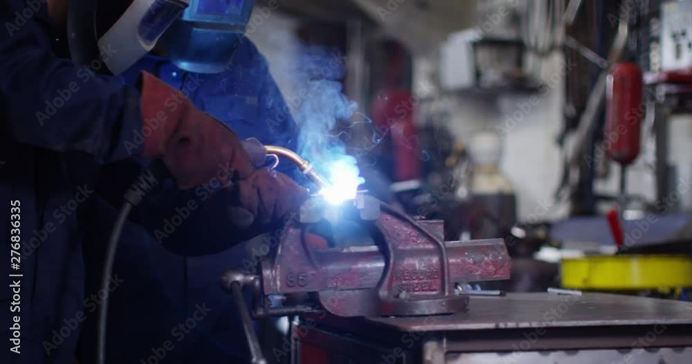 4K Smiling engineers in metal workshop take off masks to check the work. Slow motion. 4K Smiling engineers in metal workshop take off masks to check the work. Slow motion.