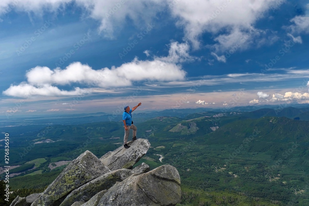 Man stretching  out  his arm and pointing to the horizon on mountain top. Victory pose. Mount Pilchuck State Park near Seattle. WA. United States of America.