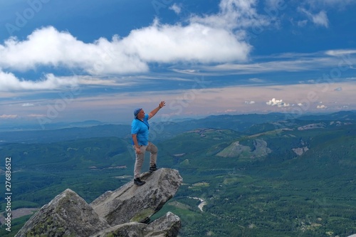 Man stretching  out  his arm and pointing to the horizon on mountain top. Victory pose. Mount Pilchuck State Park near Seattle. WA. United States of America. photo