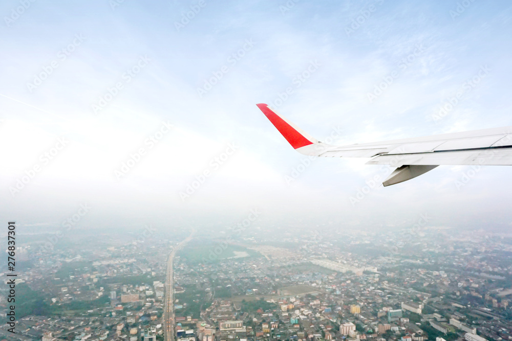 Outside aircraft window view with aircraft wing being takeoff on blue sky and higher of landscape view background.