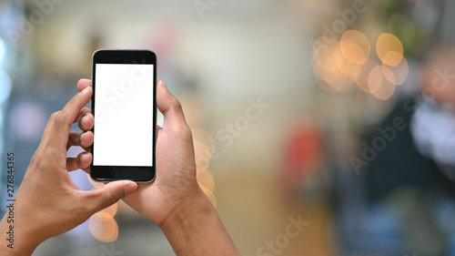 Smartphone on hands with empty screen and bokeh on blur background.